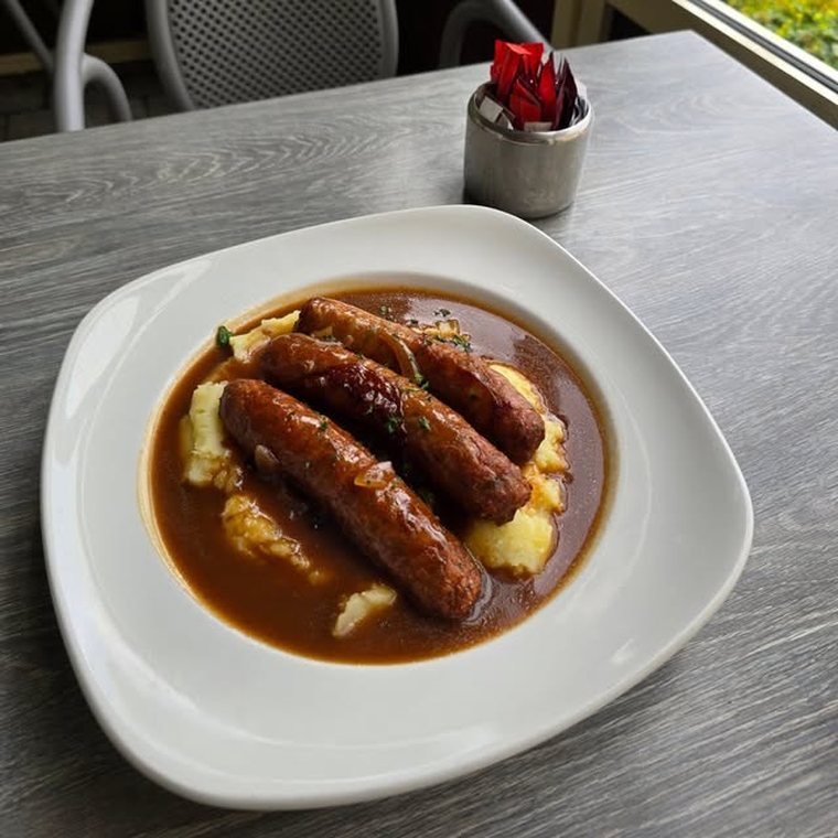Sausages and mashed potato under gravy.