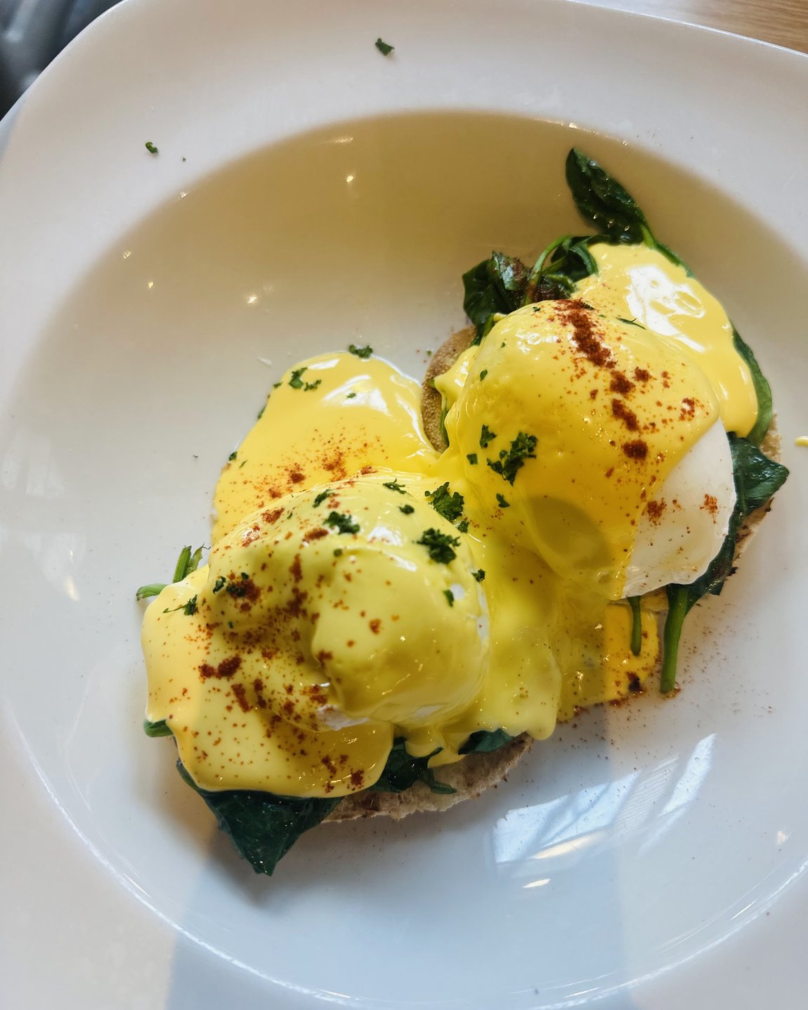 Eggs Benedict at Cates Café: two poached eggs on a toasted muffin with wilted spinach, covered in hollandaise and dusted with paprika and parsley.