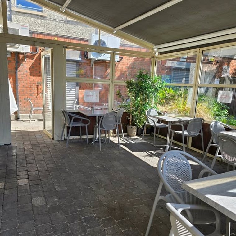 The bright glass-roofed seating area at Cates Café, with tables looking out onto greenery.
