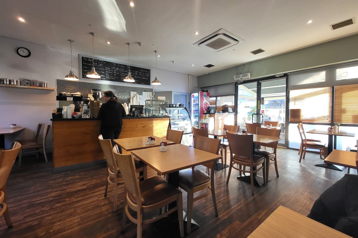The counter at Cates Café with chalkboard menus above it, pendant lamps, and wooden tables laid out in front.