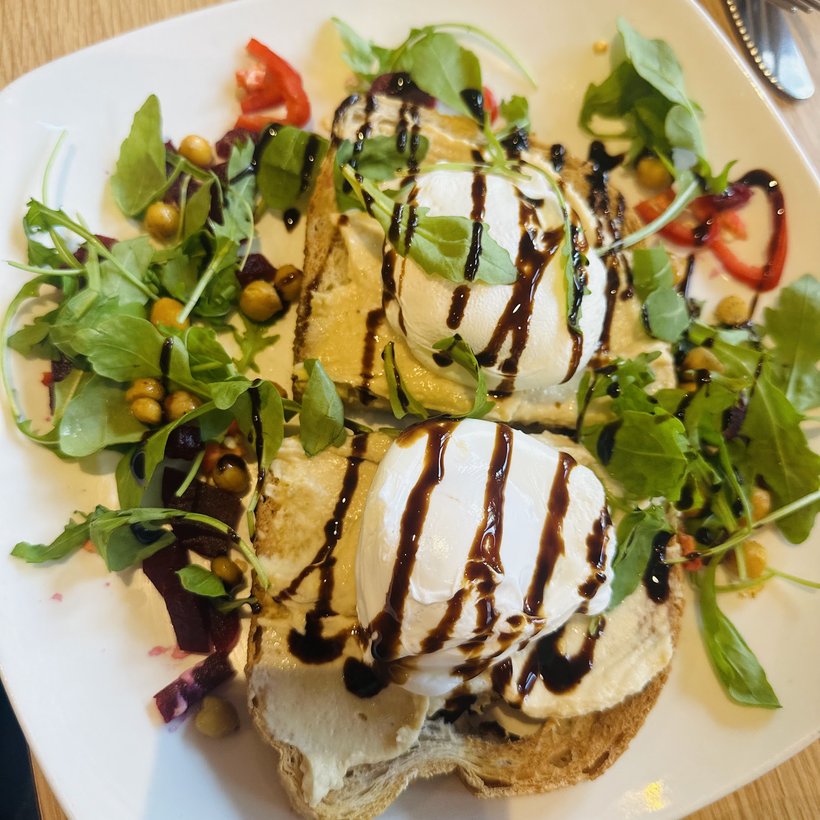 Poached egg on toast with leaves, tomato and a balsamic glaze.