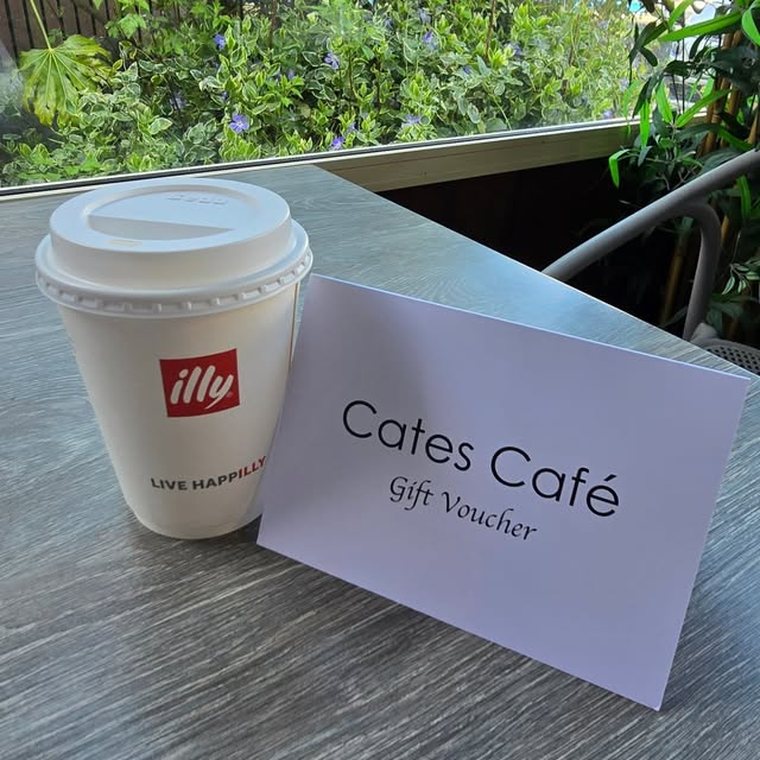 An illy takeaway cup beside a Cates Café gift voucher.
