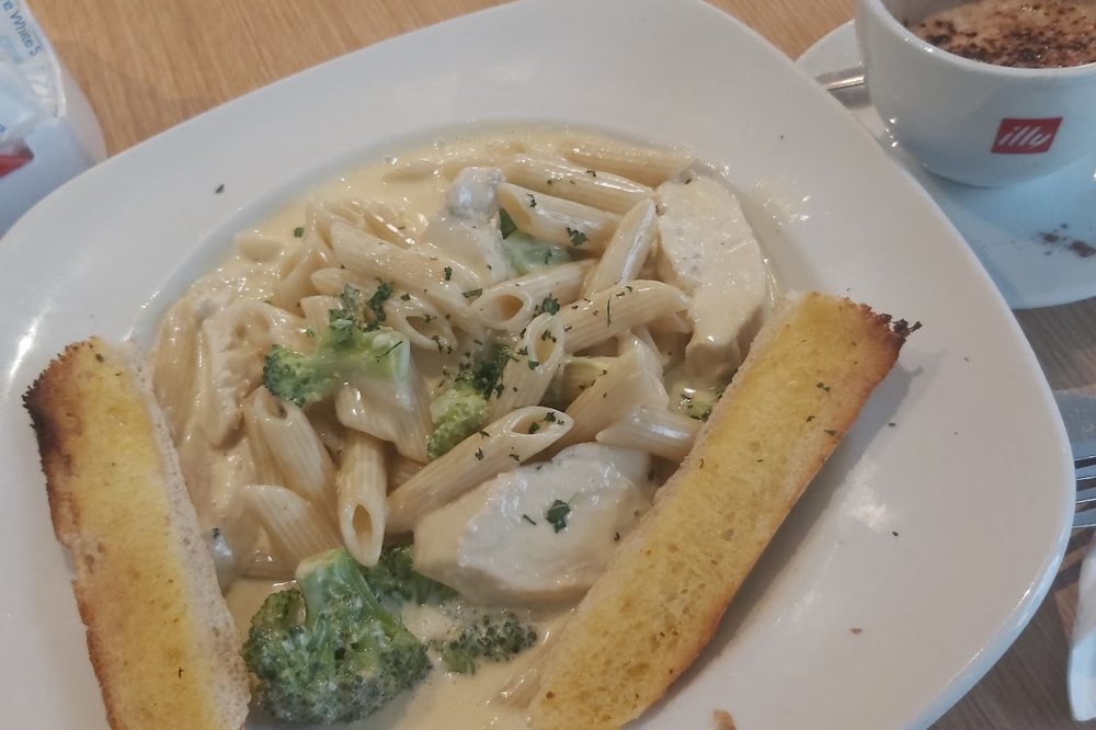 A bowl of creamy chicken and broccoli pasta with garlic bread at Cates Café.
