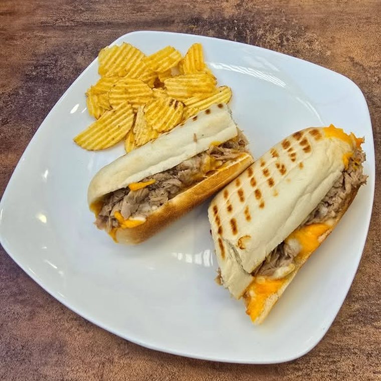 A toasted cheese sandwich cut in half with crisps alongside.